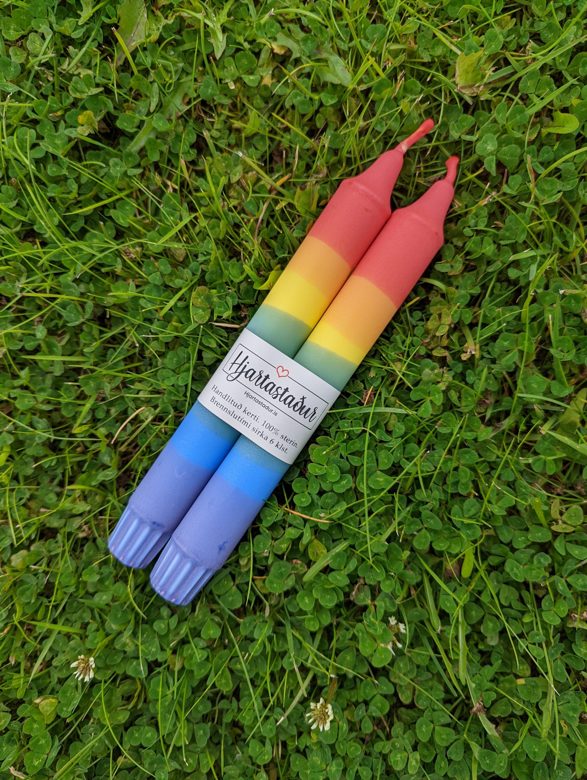 rainbow colored candles on grass
