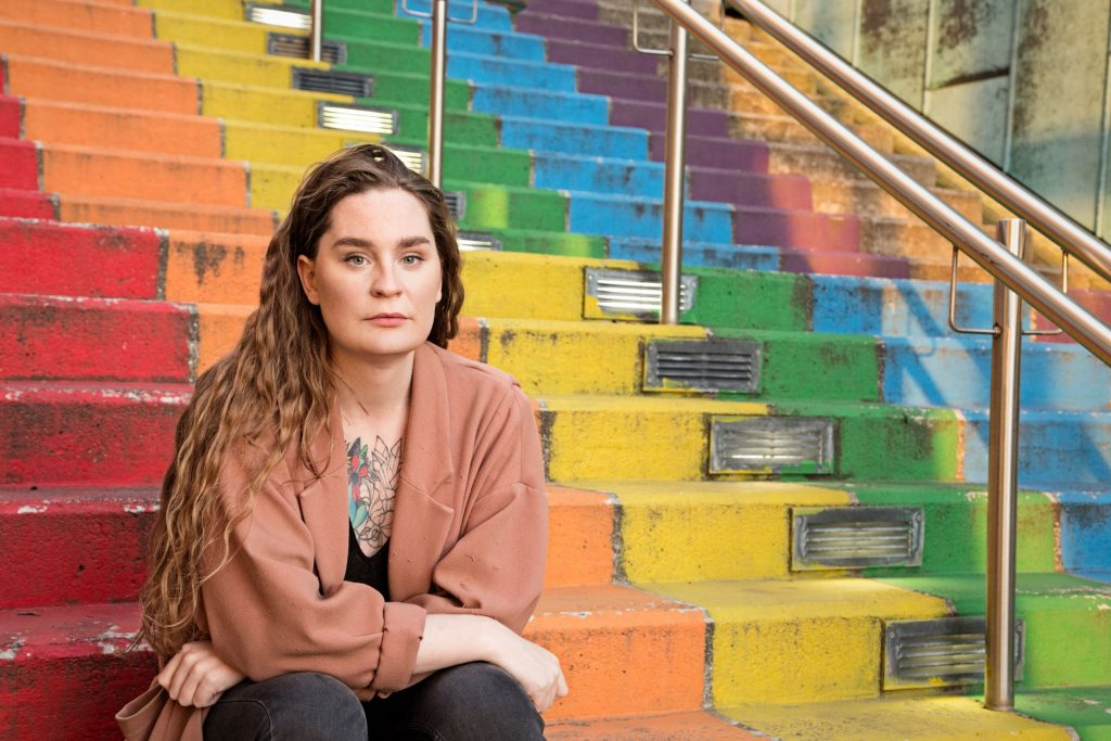 A person sits in a rainbow colored staircase